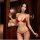 Woman modeling red qingran bikini set with butterfly hip ties and lingerie-style top in warm indoor setting.