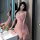 A woman poses elegantly beside a sink wearing a delicate pink lace sleepwear dress, featuring adjustable straps and a flatter...
