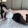 Woman lounging on bed in qingruohan milk silk bodysuit, a sexy secretary uniform outfit with white top and black skirt.