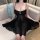 Woman wearing qingruohan black sensual lingerie set with sheer nightdress and delicate straps, seated on a sofa.