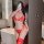 Woman in red lace bra set with sheer details and matching garter belt, posing in a modern bathroom setting.