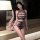 Woman modeling black sheer mesh qingruohan lingerie set with cutout bodysuit and thong in bedroom setting.