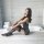 Woman in qingruohan sheer black hook-neck lingerie set, sitting by bathtub. bodycon nightdress with lace trim and stockings.