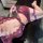 Woman wearing purple qingshe lace lingerie set with garter straps, lying on dark surface in sensual pose.