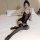 Woman wearing qingyegé black lace mesh bodysuit and sheer stockings, posing seductively on a white bed in lingerie set.
