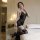 Woman modeling qingyegé black lace mesh bodysuit with sheer stockings in bedroom.