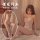 Woman wearing qingyegé sexy lingerie set - sheer bodysuit with open-crotch design and matching stockings, sitting on bed.