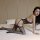 Woman wearing qingyegé sheer mesh bodysuit with open-crotch design, posing on bed in elegant black lingerie.
