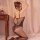 Woman wearing black qingyege lace bodysuit with sheer mesh and floral embroidery, kneeling beside vintage table.
