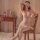 Woman wearing qingyege sheer mesh bodysuit with lace blindfold, seated on wooden chair in bedroom setting.