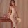 Woman wearing qingyege sheer mesh bodysuit with open-crotch design and matching stockings, posed beside wooden nightstand.