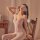 Woman wearing qingyege sheer lace bodysuit with open-crotch design, matching stockings, and floral eye mask, seated elegantly...
