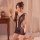 Woman in qingyege sheer mesh bodysuit with open-crotch design, holding a mirror in a cozy bedroom setting.