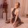 Woman wearing qingyege sexy lace bodysuit with open-crotch design, sheer mesh tight-fit one-piece outfit, kneeling on bed.