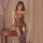 Woman wearing qingyege sexy lace bodysuit with sheer mesh and european style design, posing elegantly by a wooden table.