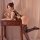 Woman in qingyege sexy lingerie set with sheer mesh stockings and open-crotch top, posing seductively at wooden vanity.