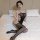 Woman wearing qingyege sheer mesh bodysuit and thigh-high stockings on bed, seductive lingerie set.