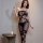 Woman wearing qingyege sheer black lace bodysuit with open-crotch stockings, posing indoors beside candlelit table.