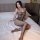 Woman wearing qingyege sheer lace bodysuit, a seductive transparent mesh one-piece outfit for adults, sitting on bed.