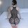 Woman wearing qingyege sheer black bodystocking with geometric cutouts, sitting on bed.