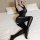 Woman wearing qingyeguo sheer black bodysuit with lace trim and open-crotch design, posing on a white bed.