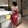 A woman stands facing away from the camera, wearing a red sheer hanfu dress inspired by the style of the ancient city of dunh...