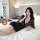 A woman lounges on a bed wearing a black lace dress with floral patterns, featuring a plunging neckline and three-quarter sle...