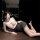 Woman in qqny pure allure lingerie set – white top, gray skirt, lace eye mask, posing seductively on table.
