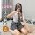 A woman wearing a white blouse with a tie and plaid skirt sits on the floor taking a selfie. the outfit features playful elem...