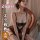 Woman modeling qqny pure allure black lace lingerie set with fishnet stockings, seated on ornate chair in soft-lit bedroom.