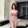 Woman wearing qqny pure allure sleepwear set – elegant red and white lace lingerie with nurse hat, standing in modern bedroom...