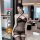 Woman wearing qqny pure allure sleepwear set — elegant black sheer lingerie with crisscross straps, in luxury hotel room.