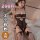 Woman modeling black lace qqny pure allure sleepwear set with sheer bodysuit and fishnet stockings on bed.