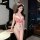 Woman wearing qqny pure allure sleepwear set – red and white lace lingerie with nurse hat, posing in modern bedroom.