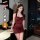 A woman stands confidently wearing a form-fitting, deep red dress with halter straps. the setting appears luxurious, featurin...