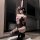 A woman poses in a sensual black sleepwear set with pink bunny ears and bows, featuring sheer fabric and high heels.