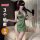 Woman wearing green satin qqny pure allure lingerie set with deep v-neck, side slits, and feather accessory.