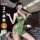 Woman modeling qqny pure allure green satin lingerie set with deep v-neck, side cutouts, and matching garter straps on bed.