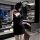 Woman wearing black qqny pure & sexy knotted neckline sleep dress in modern lounge, body-con silhouette perfect for date nigh...