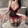 A woman poses in a black and pink lace corset dress with underwires, paired with sheer stockings, creating a sensual office u...