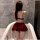 Woman in qqny seductive lounge set, featuring a burgundy bralette and pleated skirt, posing in a marble bathroom.