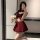 Woman in qqny seductive lounge set, red and black lingerie with bow details, holding a plush toy, posing in mirror.