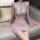 Woman in pink lace qqny seductive maid costume lingerie set, no-remove design, posing on sofa.