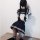 Back view of woman in navy and white sailor-style short skirt outfit with braided hair, kneeling on floor.