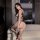 Woman wearing qqny sexy sheer lingerie set with mesh bodysuit and fishnet stockings, posing in a modern room.