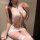 A woman wearing a white lace bodycon dress with halter neck design, featuring sheer mesh and thigh-high stockings, exuding se...