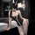 Woman wearing black rabbit girl lingerie set with lace trim, bunny ears, and white stockings in a modern bathroom setting.