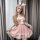 A woman wears a cute bunny-themed outfit, featuring a pink dress with white lace trimmings, fluffy pom-poms, and bunny ears, ...