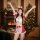 A festive scene featuring a woman wearing a red christmas bunny girl costume, complete with antlers and a maid apron, set aga...
