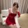 A woman poses elegantly in a red velvet dress featuring sheer lace sleeves, perfect for festive occasions or intimate wear.